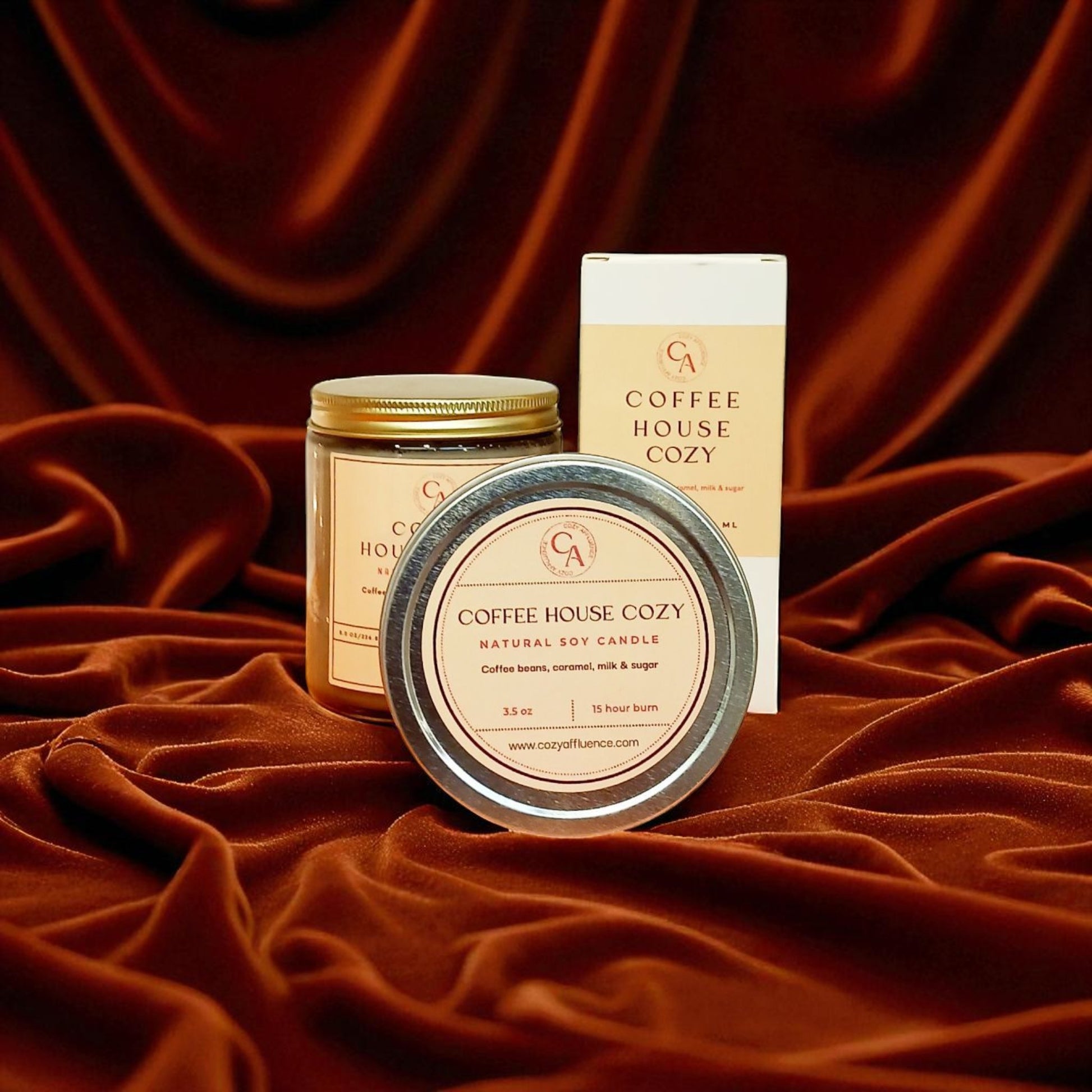 Candle and packaging labeled 'Coffee House Cozy' on a textured brown fabric background