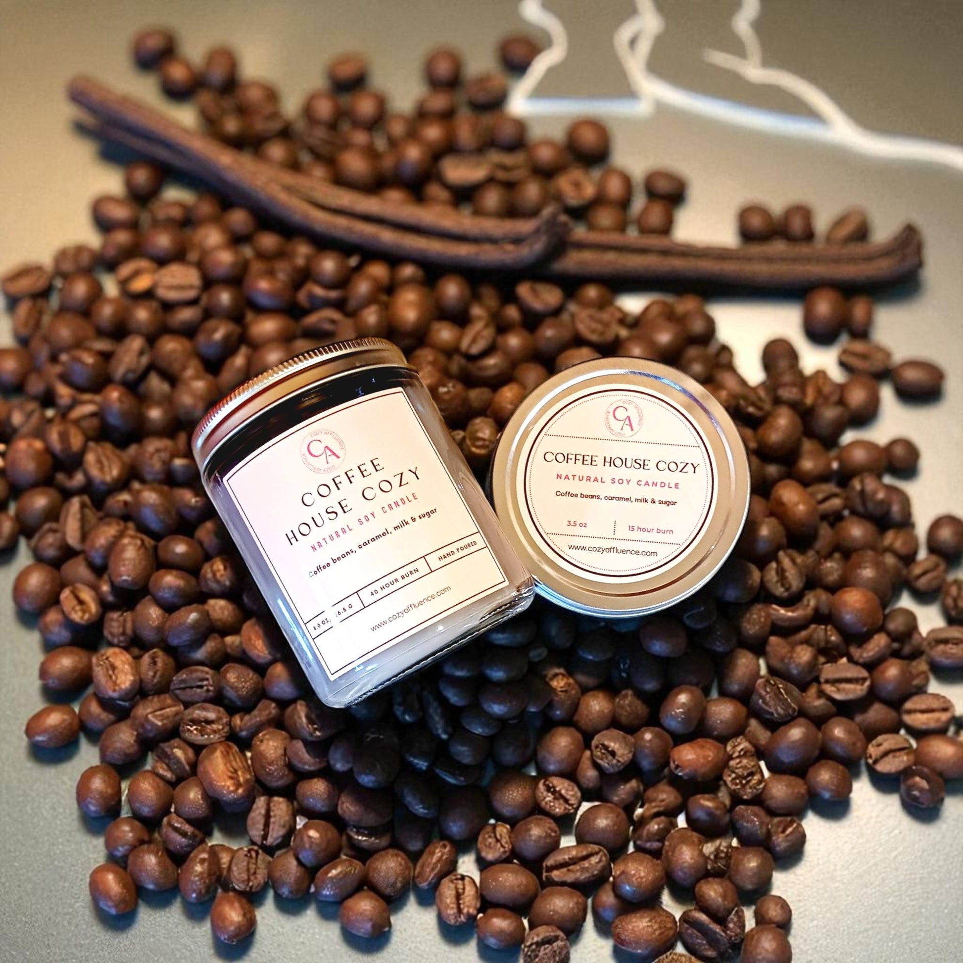 Two candles labeled 'Coffee House Cozy' on a bed of coffee beans.