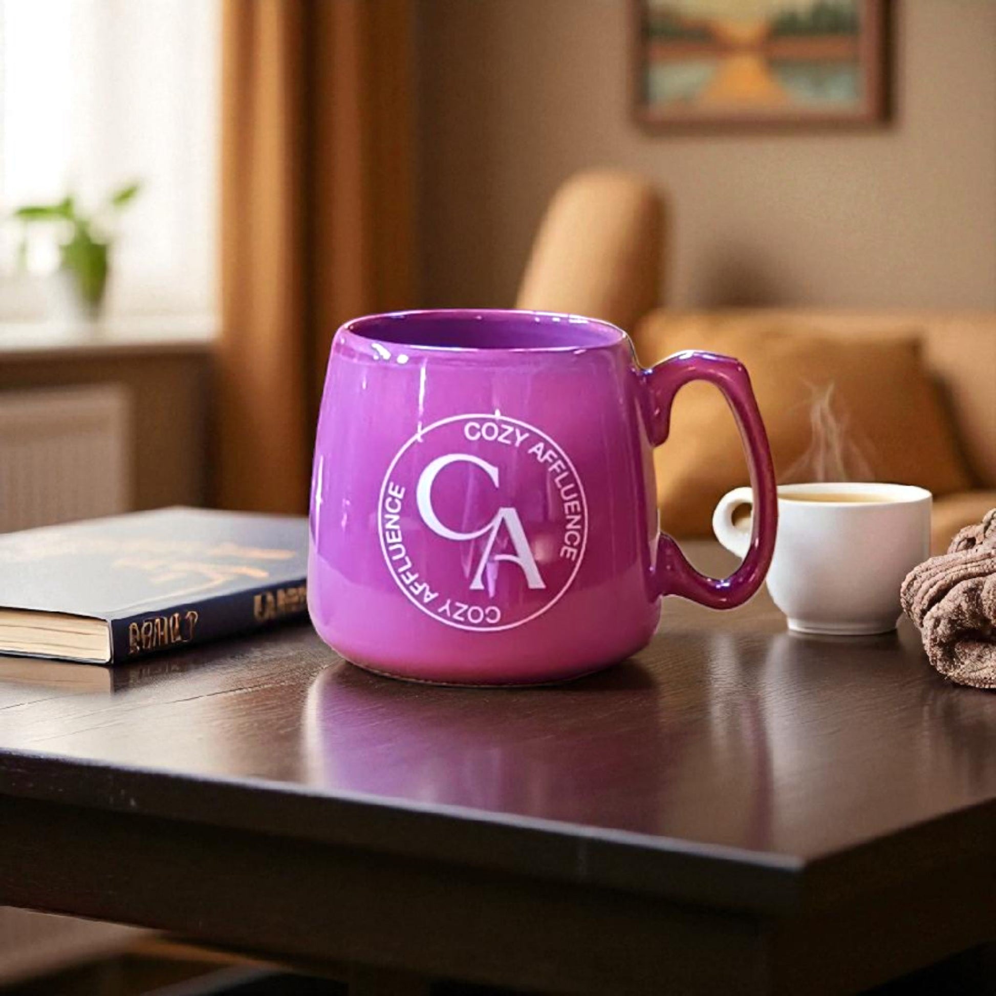 Purple mug with 'Cozy Affluence' logo on a table with a book and coffee cup in a cozy room.