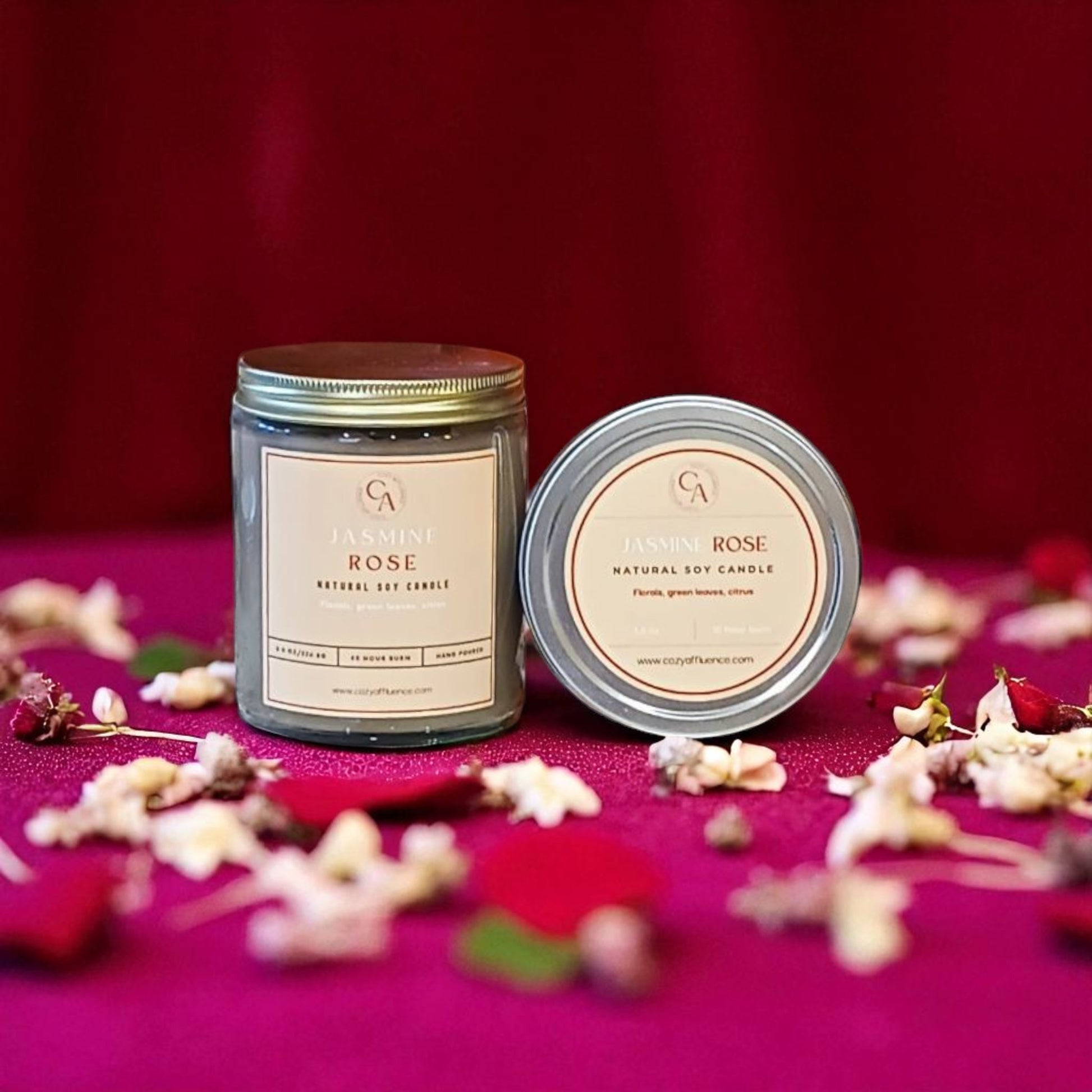 Two candles labeled 'Garden Rose' on a pink surface with flowers.