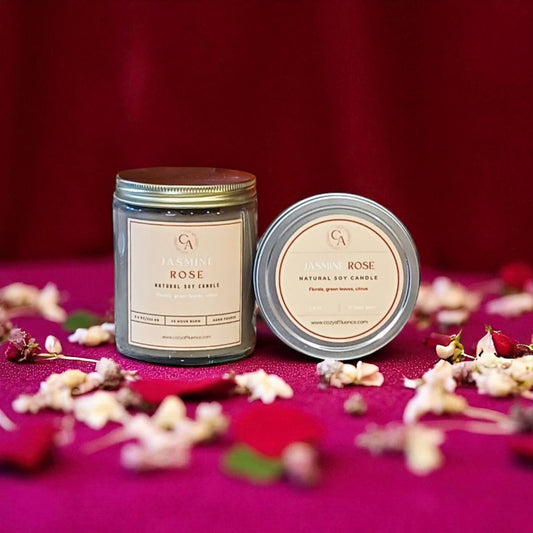 Two candles labeled 'Garden Rose' on a pink surface with flowers.