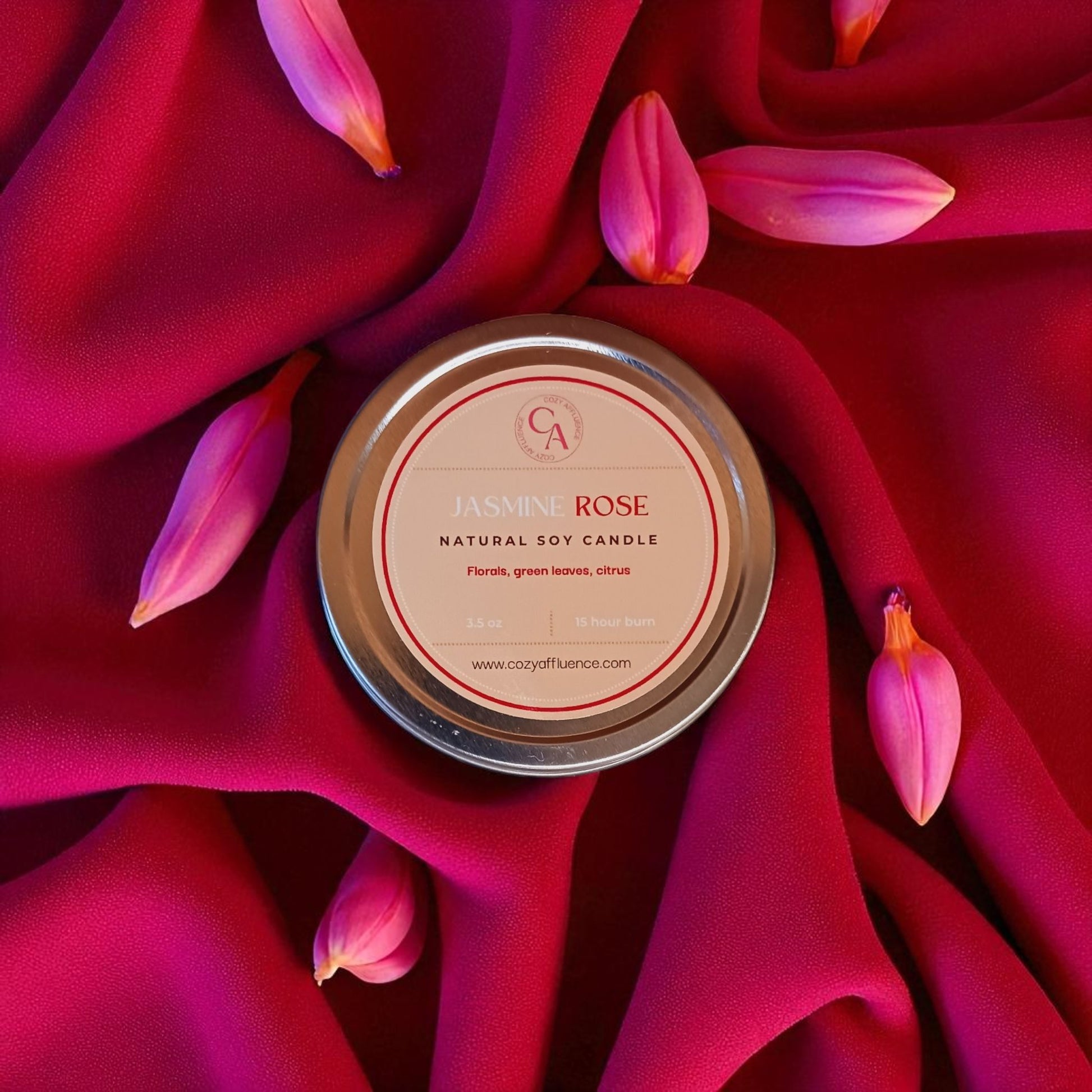 Candle tin labeled 'Tuscan Rose' on a red fabric background with pink tulip petals.