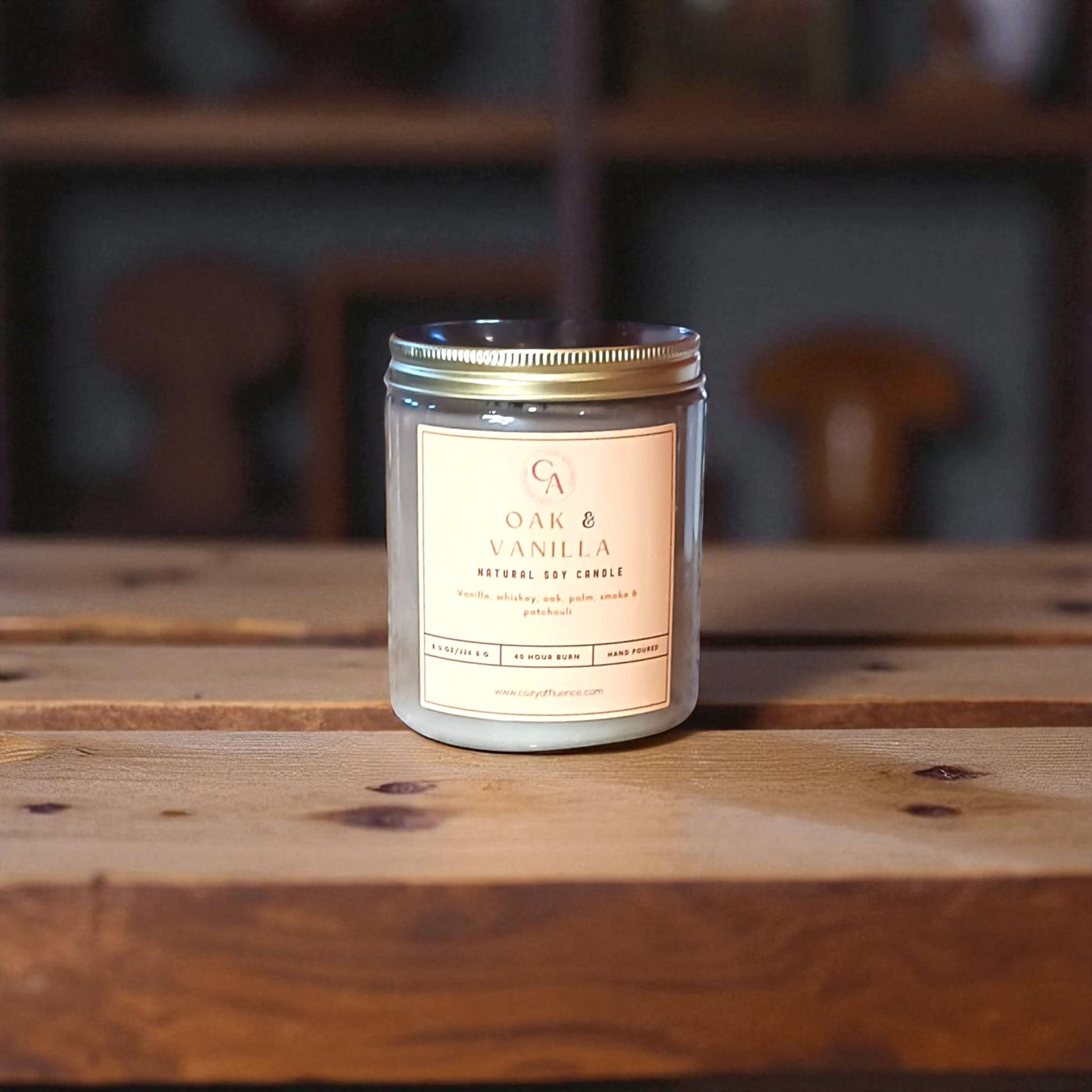 Candle labeled 'Oak & Vanilla' on a wooden surface with a blurred background.