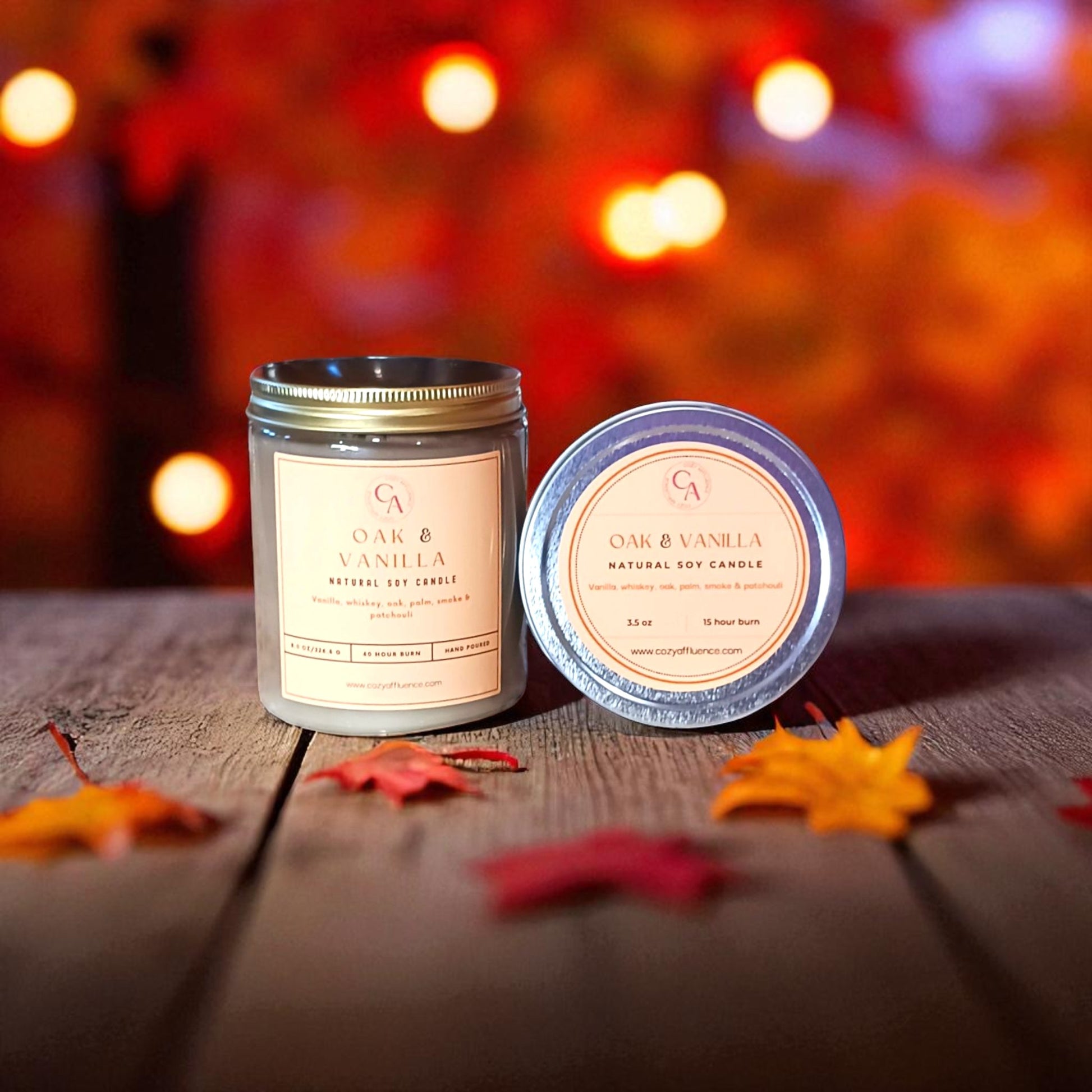 Two candles labeled 'Oak & Vanilla' on a wooden surface with blurred lights in the background.