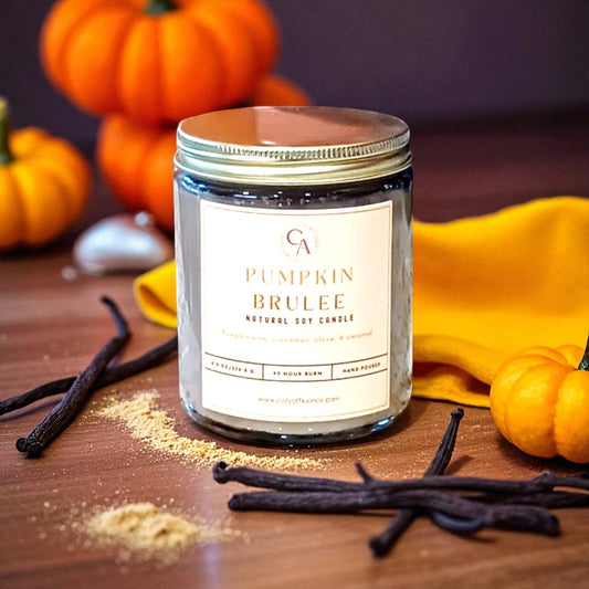 Pumpkin Brulee candle with pumpkins and vanilla beans on a wooden surface.