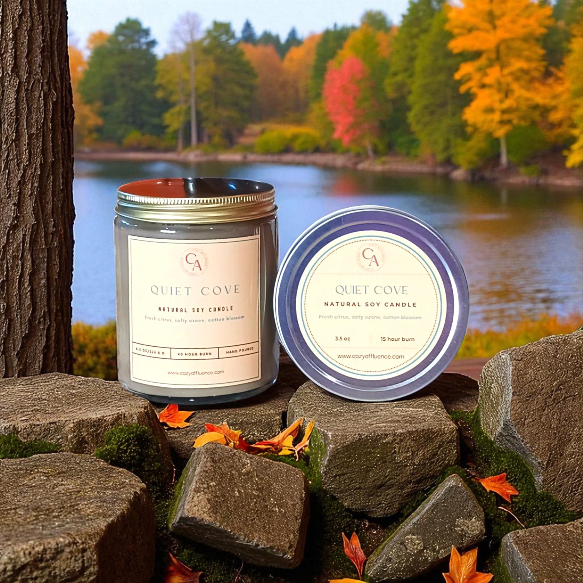 Two candles labeled 'Quiet Cove' on rocks with a scenic background of trees and water.