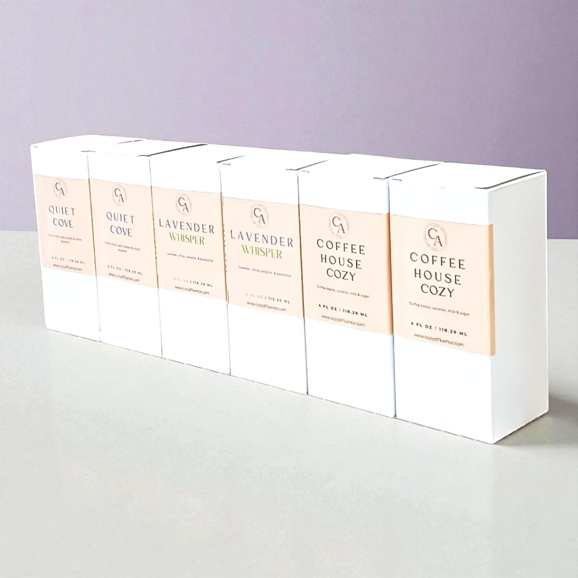 Set of white room spray boxes with product names on a light gray surface and light purple background