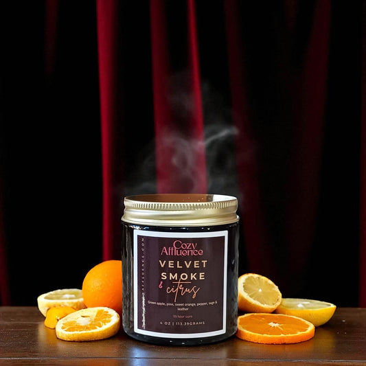 Candle labeled 'Velvet Smoke & Citrus' with orange slices on a dark background