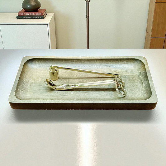 Wooden tray with candle wick cutter and candle snuffer on top of a light-colored surface