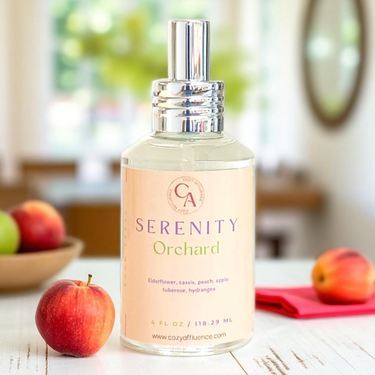 Bottle of Serenity Orchard room spray sitting next to apples on a table.