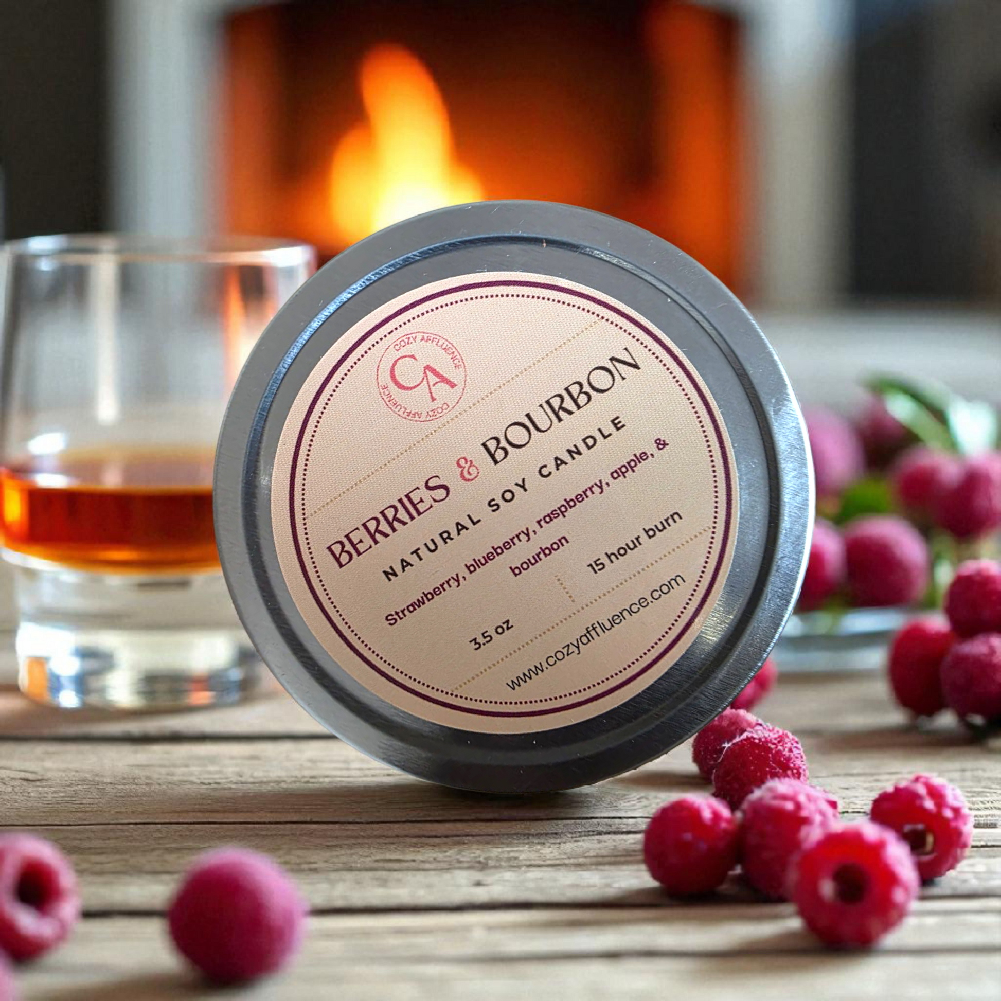Candle labeled 'Berries & Bourbon' with raspberries and a glass of liquid in front of a fireplace.