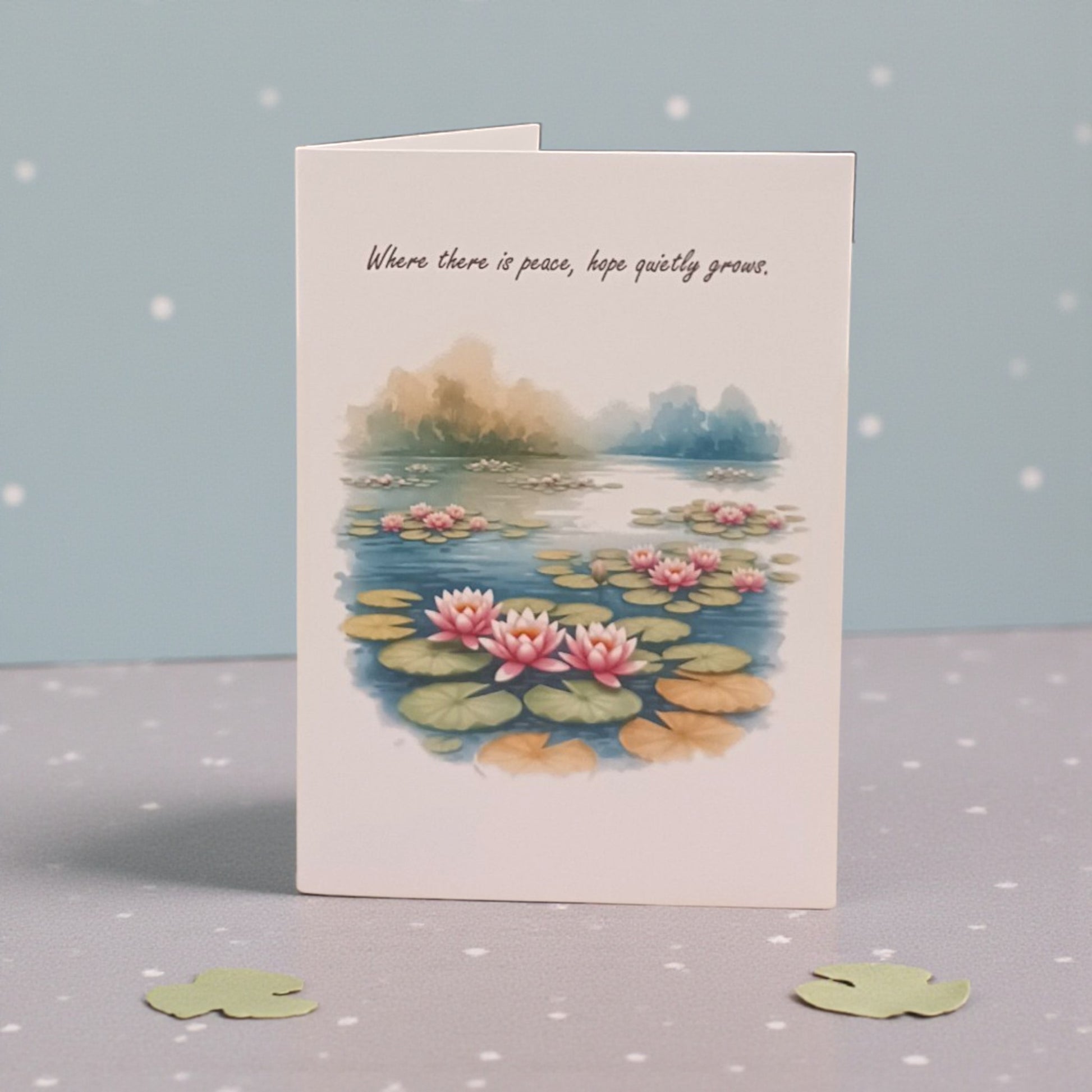 Greeting card with waterlily design and text on a gray surface