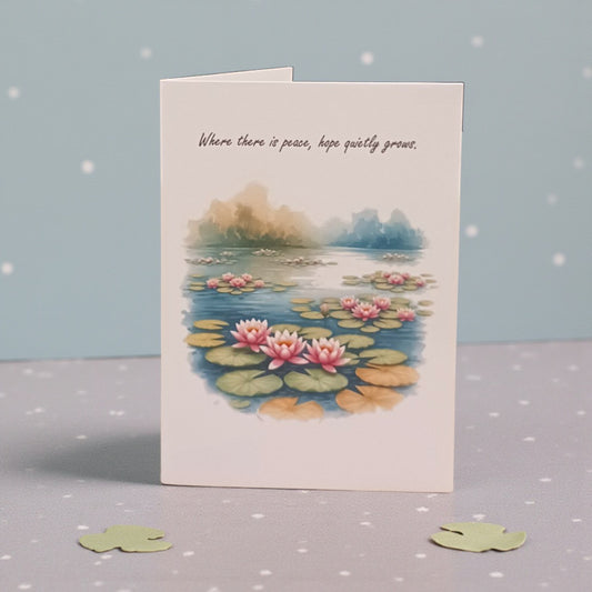 Greeting card with waterlily design and text on a gray surface