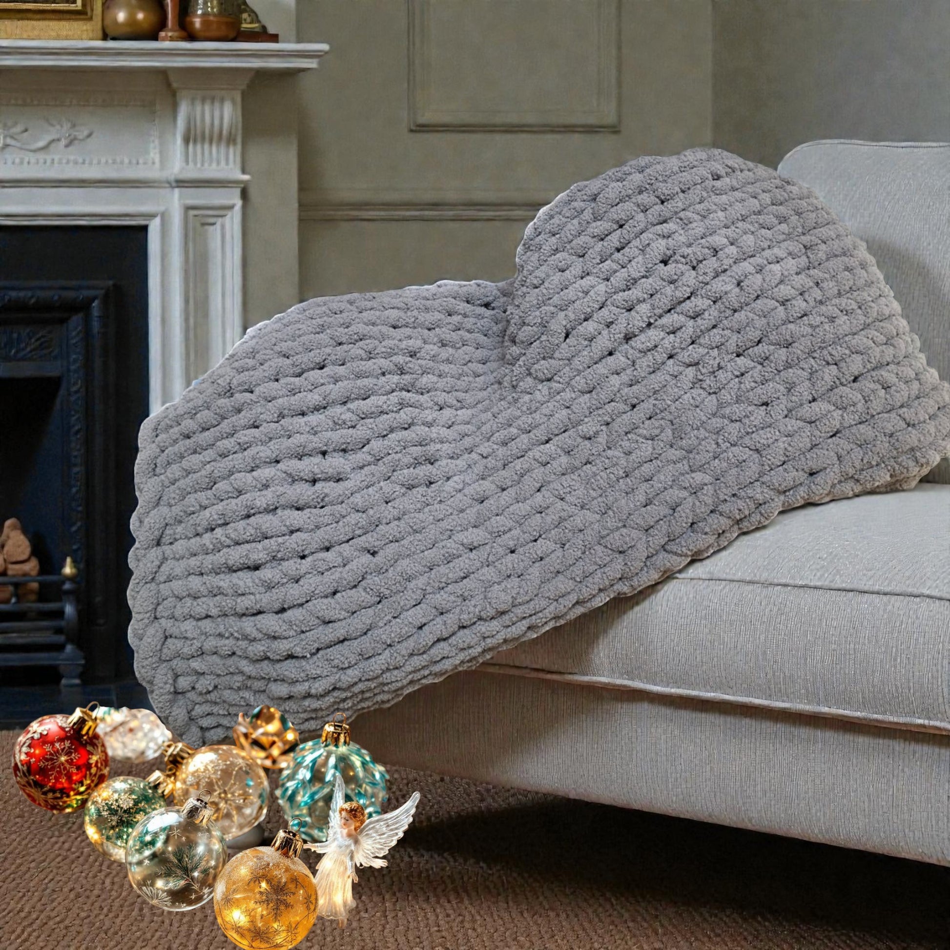 Gray textured blanket draped over a sofa in a living room with Christmas ornaments on the floor.
