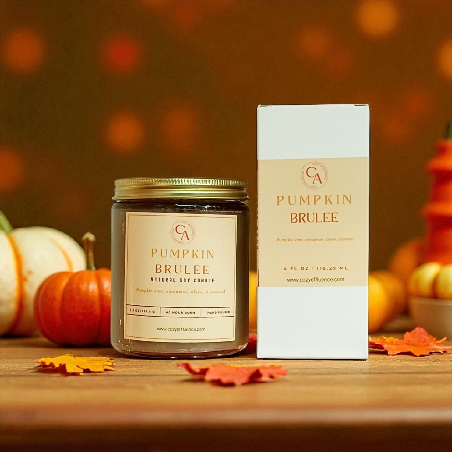 Pumpkin Brulee candle and packaging with pumpkins and leaves on a wooden surface