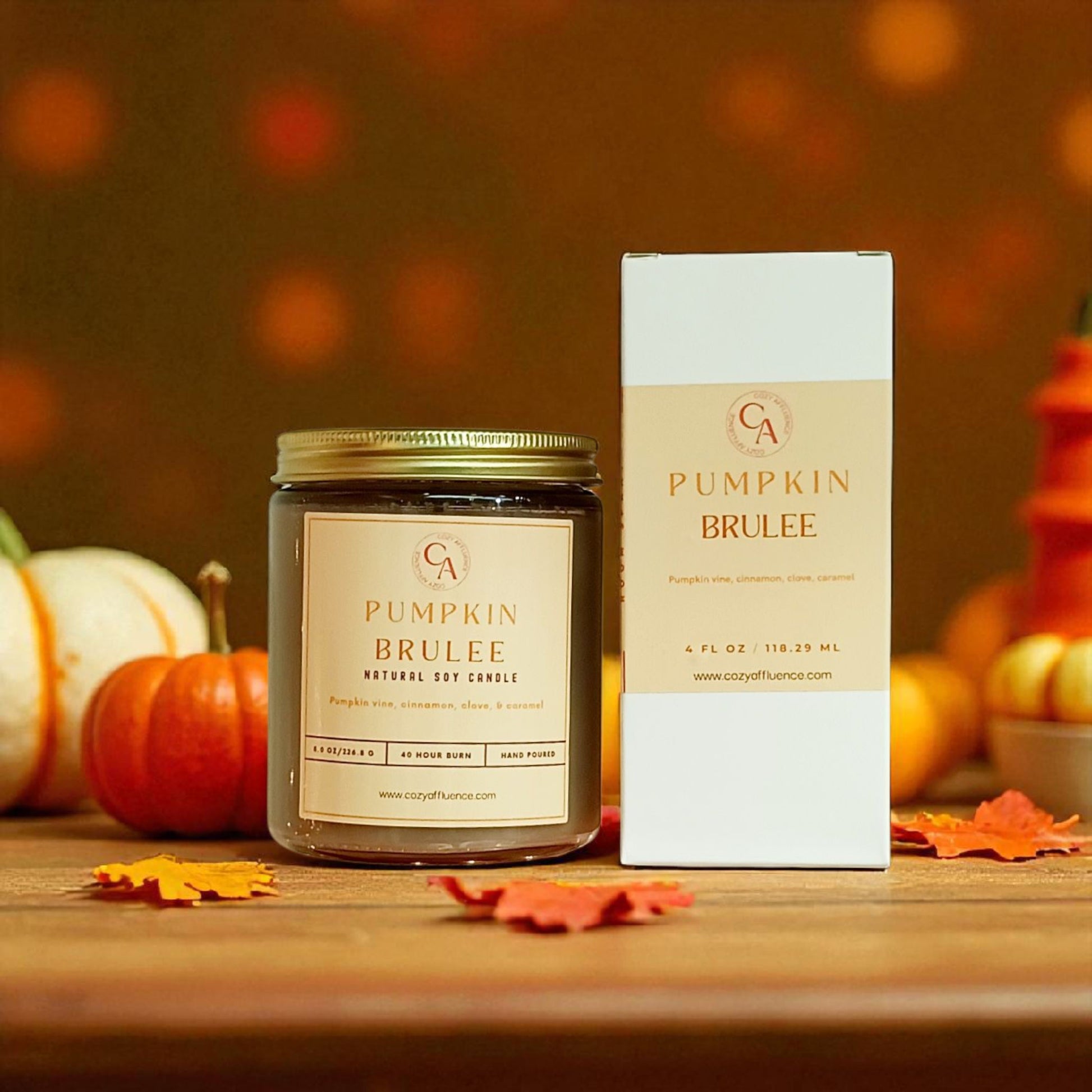 Pumpkin Brulee candle and packaging with pumpkins and leaves on a wooden surface