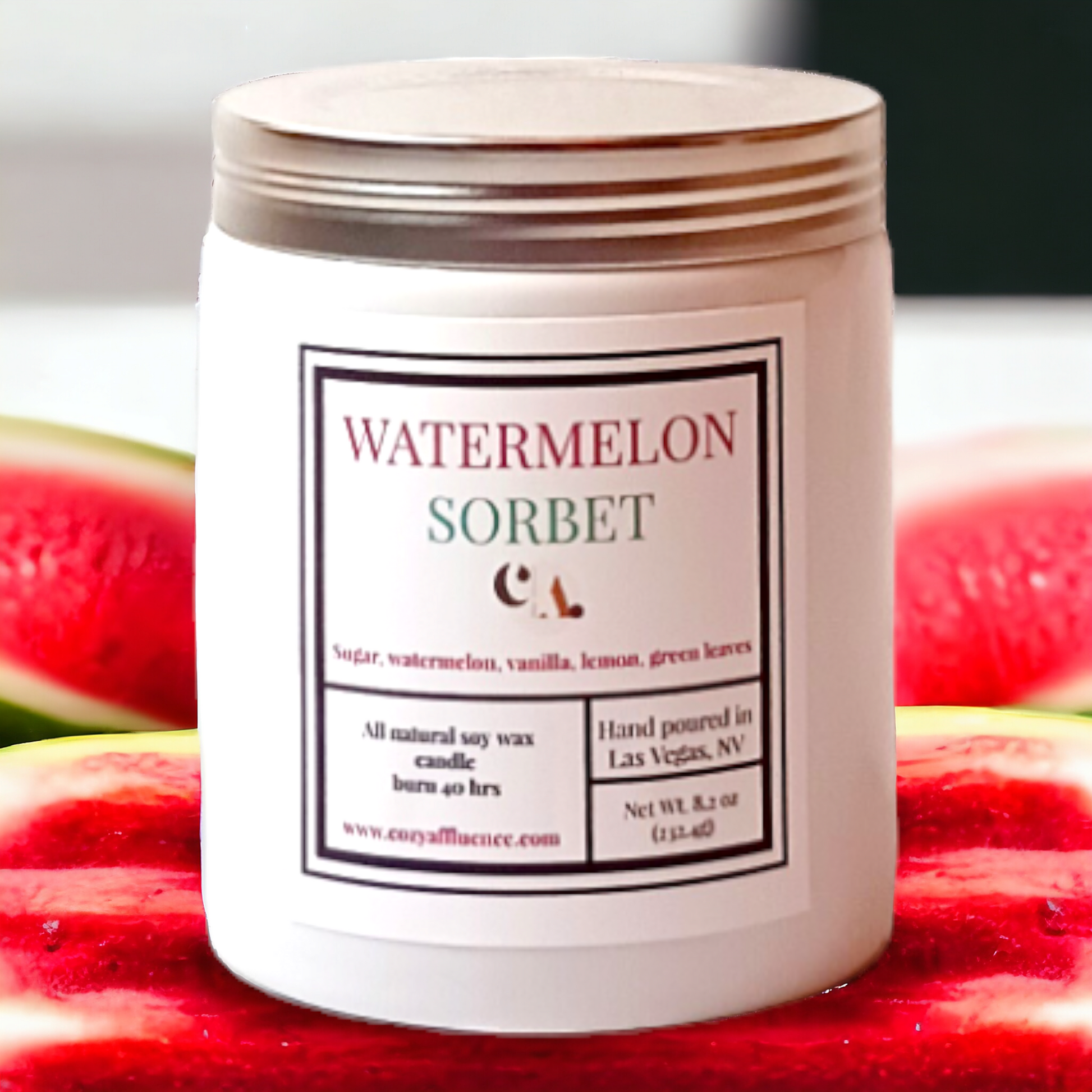 A white jar candle labeled "Watermelon Sorbet" with ingredients listed as sugar, watermelon, vanilla, lemon, and green leaves, and details about its 40-hour burn time and Las Vegas origin, is shown in front of two cut watermelon halves.