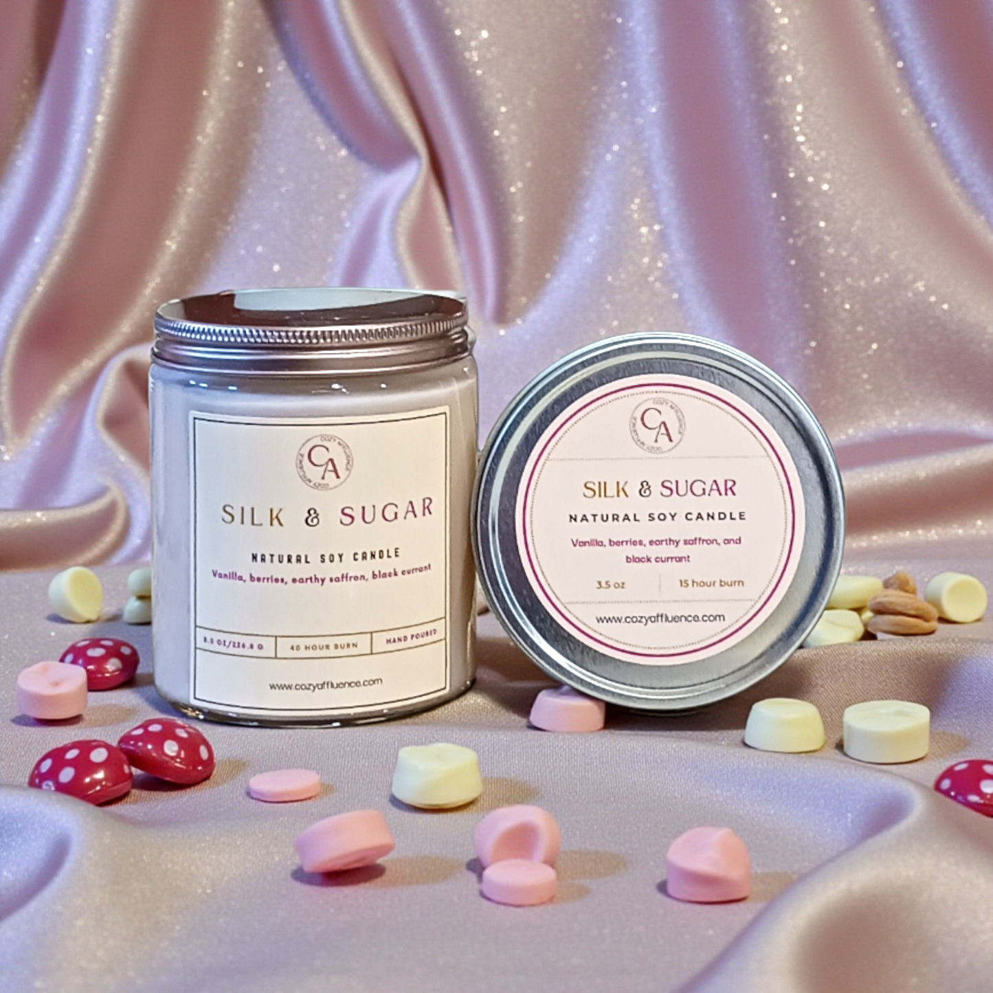 Two candles labeled 'Silk & Sugar' on a textured surface with colorful candies.